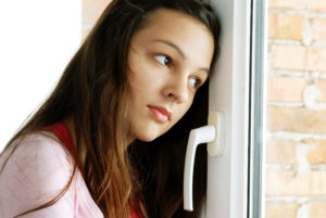 En tankefull jente som ser ut av vinduet. Det er mange som bekymrer seg rundt koronavirus