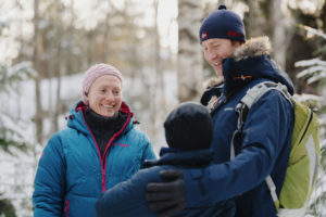 To voksne, et barn på tur i vinterskog.