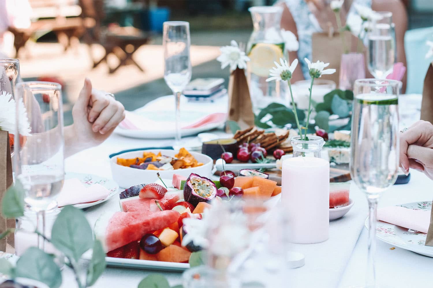 et dekket bord i sommerlige omgivelser fylt med mat og drikke