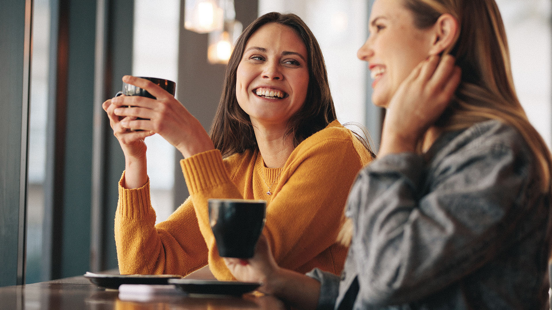 To damer som smiler og drikker kaffe