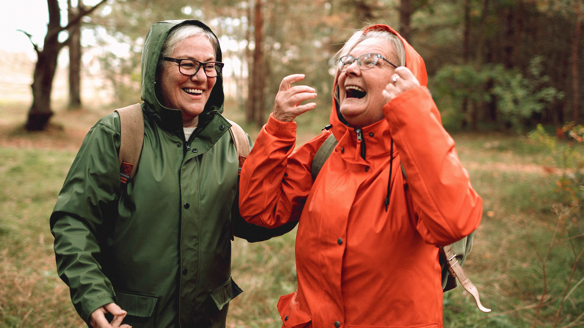 To eldre damer er i godt humør på tur i skogen