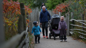 Familie med vogn går på tur blant høstblader