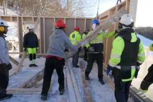 Elever i verneklær setter opp en vekk på et bygg. De har hjelm på hodet