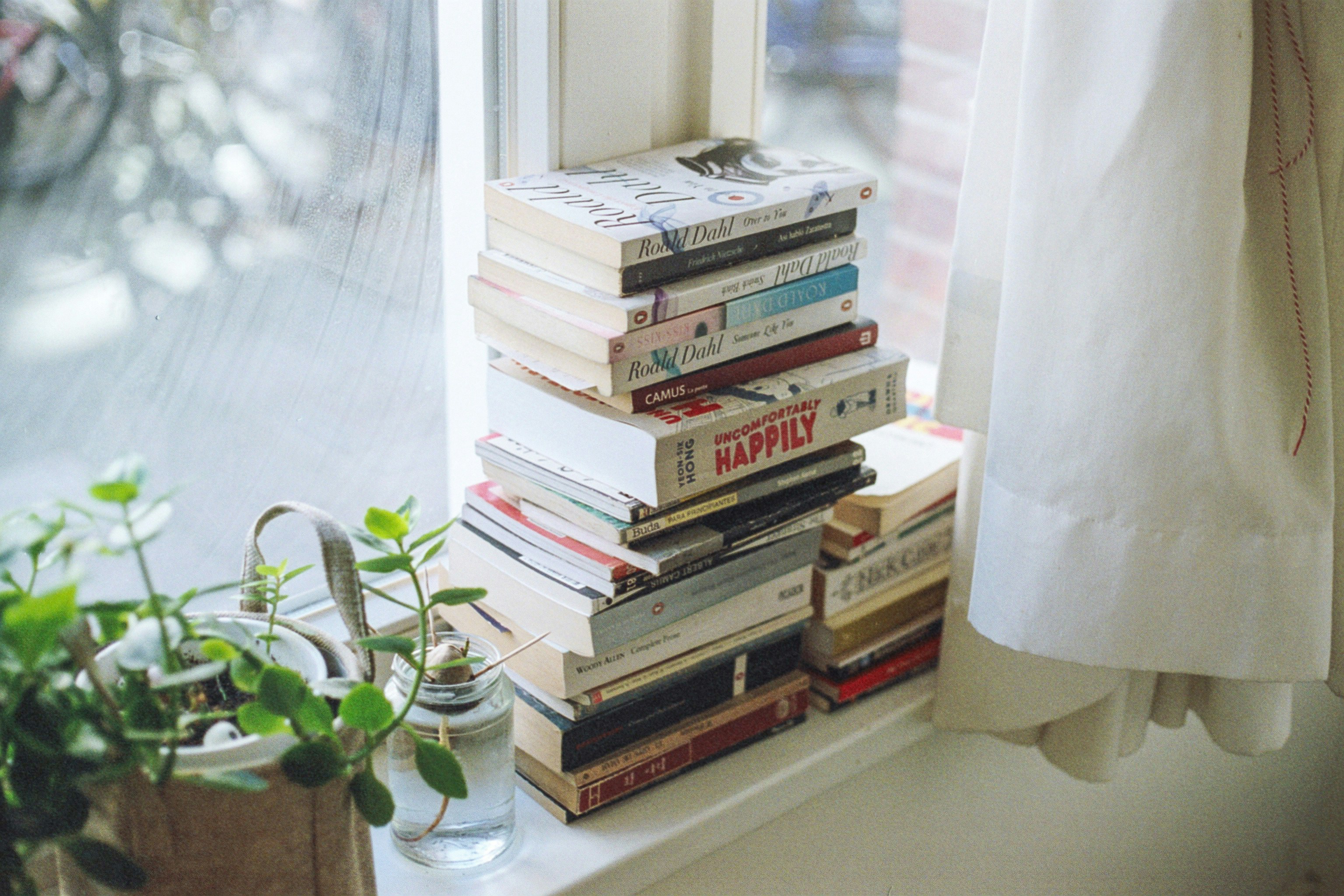 En stabel med bøker i en vinduskarm.