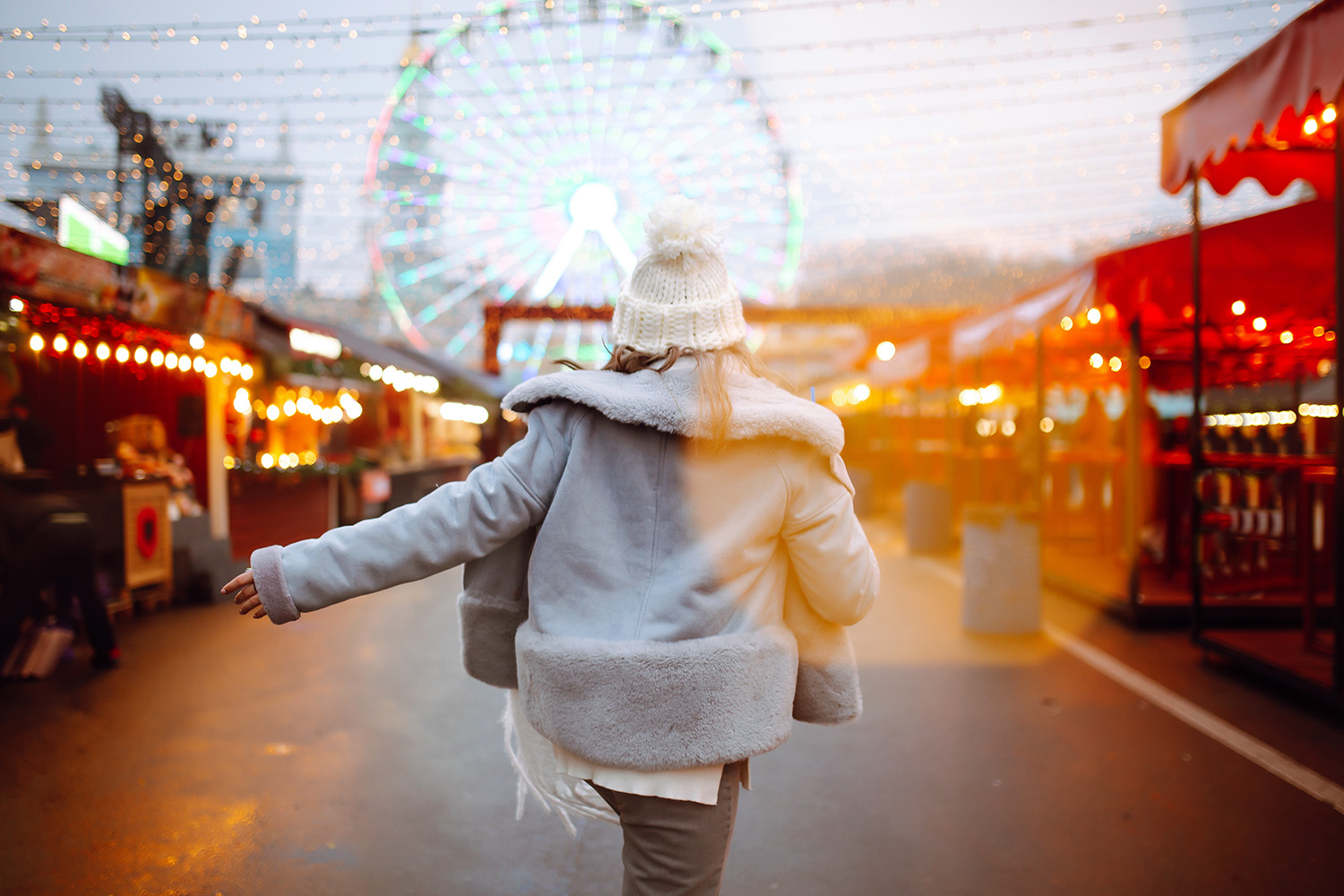 jente med lue som går lystig inn i et julemarked